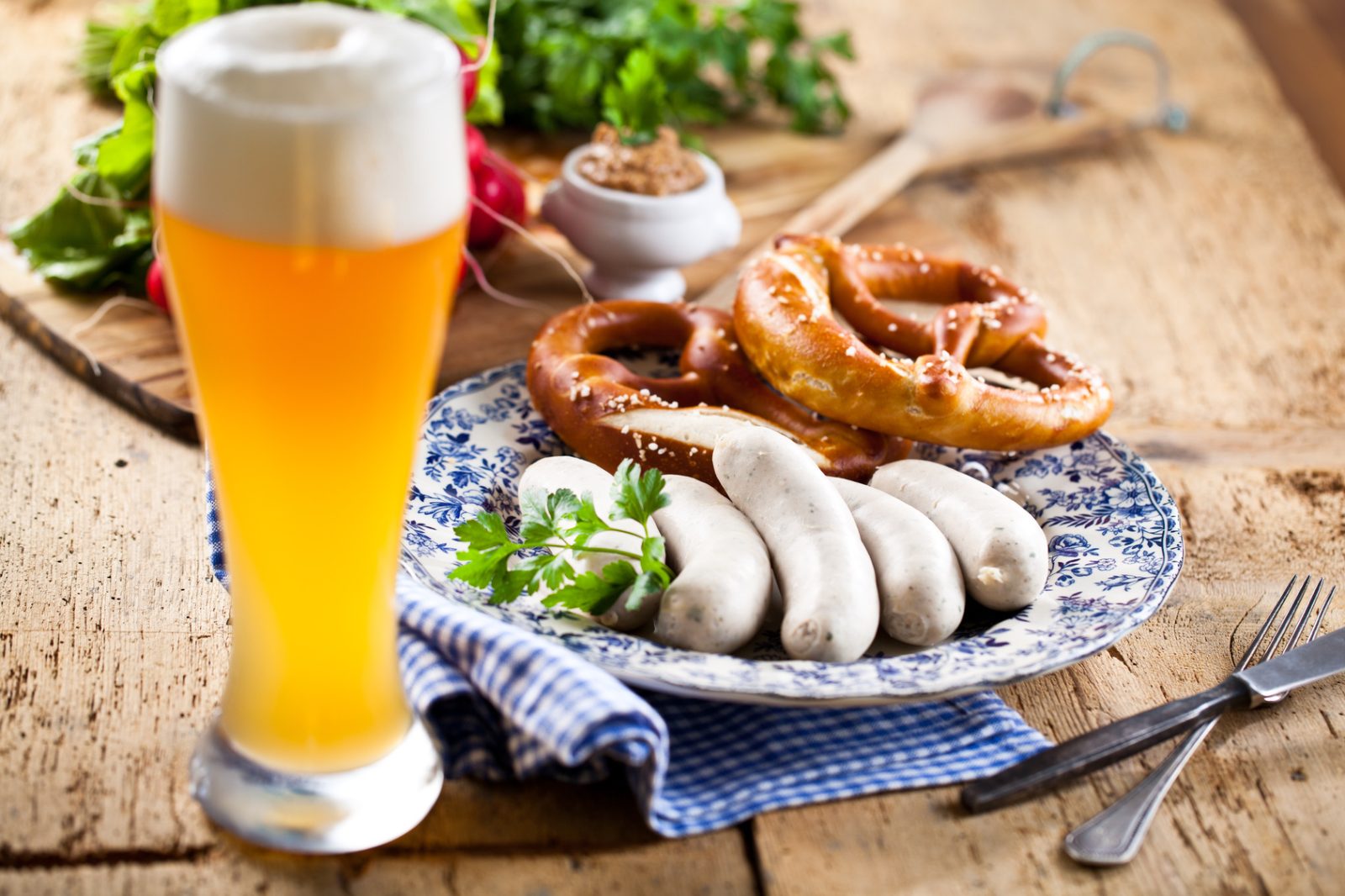 Münchner Weißwurst mit Brezn, süßem Senf und Weißbier auf rustikalem Holztisch – Weisswurst essen in München